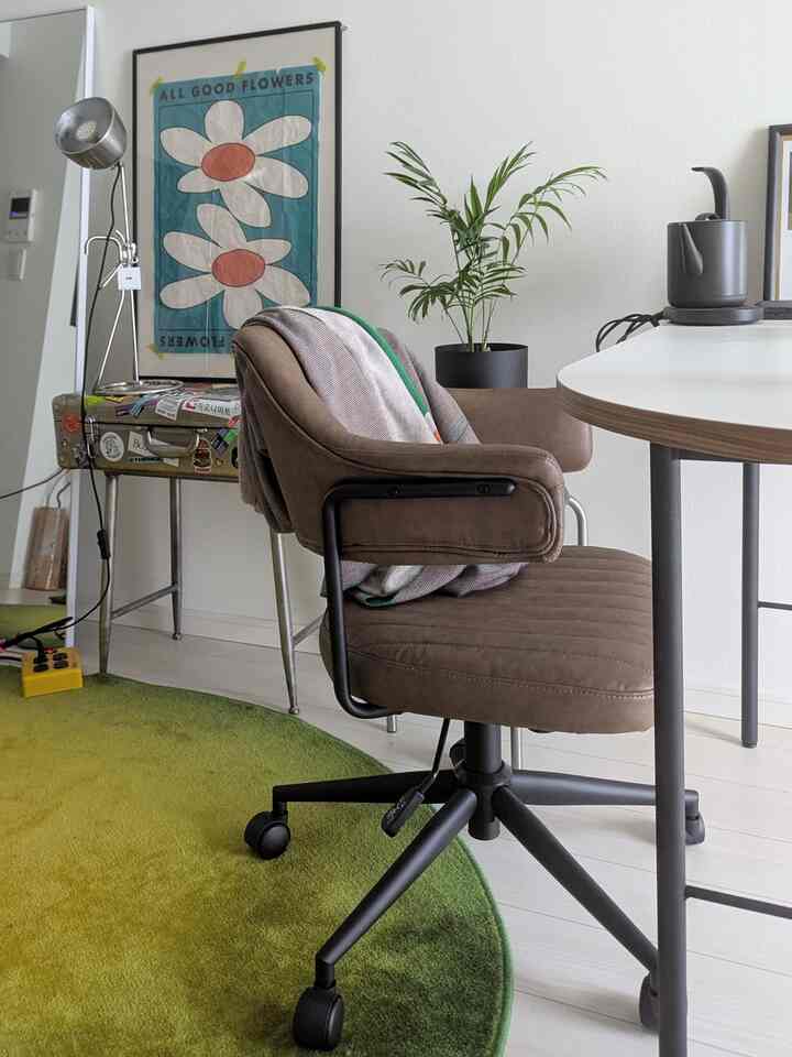 白い壁のダイニング、ブラウンのダイニングチェアとグリーンのラグが配置されたモダンで自然な雰囲気のあるインテリア