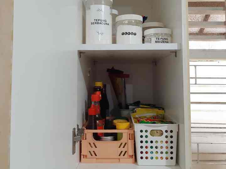 White-toned pantry cabinet interior featuring assorted kitchen ingredients and containers neatly organized