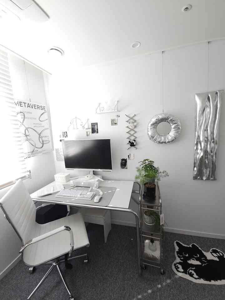 白とシルバーのモダンな書斎、コンピューターデスクとオフィスチェア、植物が配置された清潔感のある作業空間