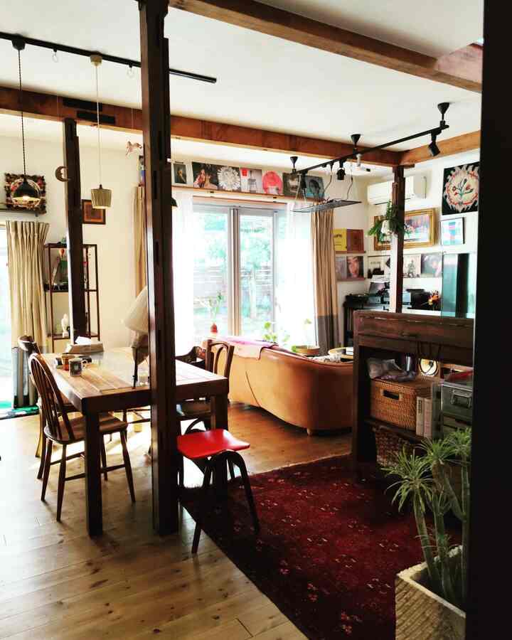 Cream white walls with wood tone living room featuring vintage sofa, dining table, and a red stool in a cozy atmosphere