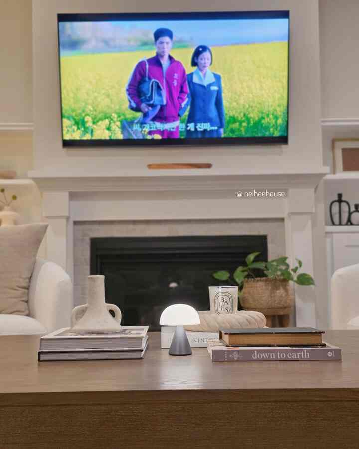Cozy living room with white walls and fireplace, featuring a wooden coffee table and soft lighting in a simple interior design