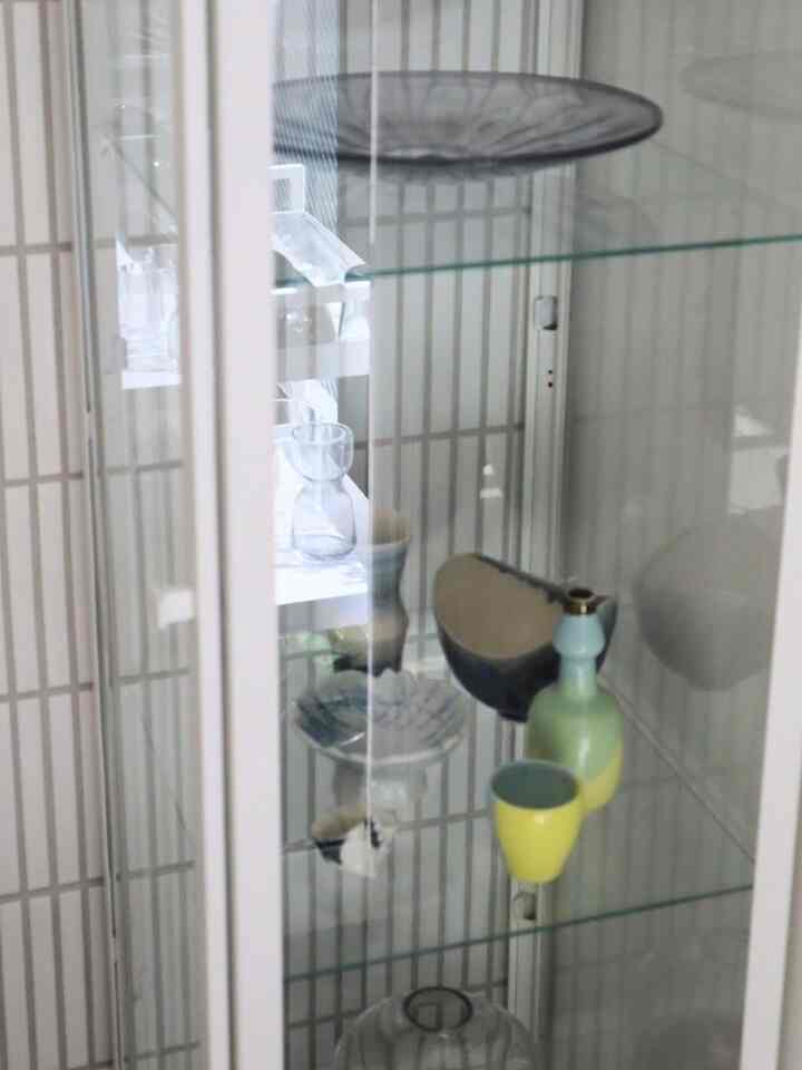 白を基調としたリビングにBLÅLIDENのガラス飾り棚が配置され、作家の器が美しく並ぶ印象的な空間