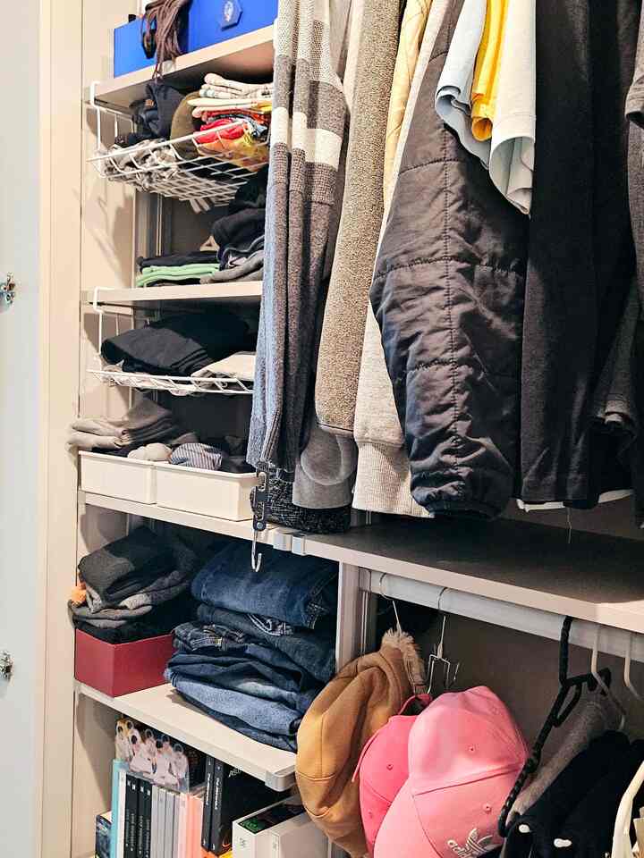 白い棚と多様な服が掛けられたウォークインクローゼット、ダイソーのワイヤーバスケットで整頓された収納力あるインテリア