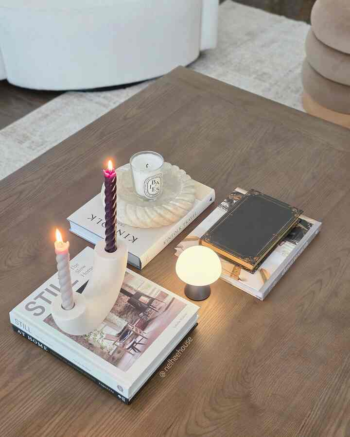 A natural-colored living room coffee table featuring lit candles and a mini mushroom lamp creating a cozy atmosphere