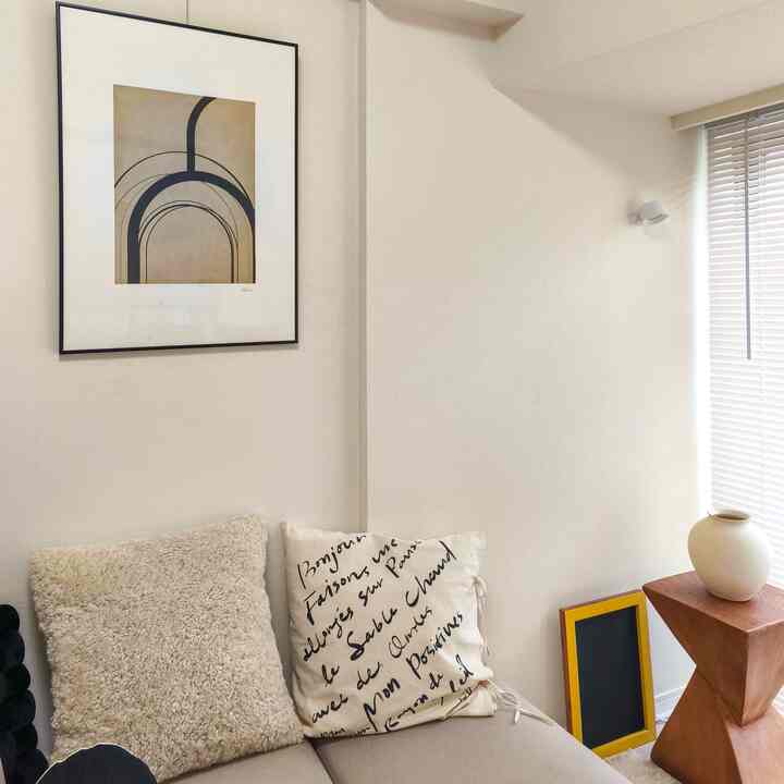 Natural toned single household living space featuring cushions on sofa and an art poster, creating a cozy atmosphere