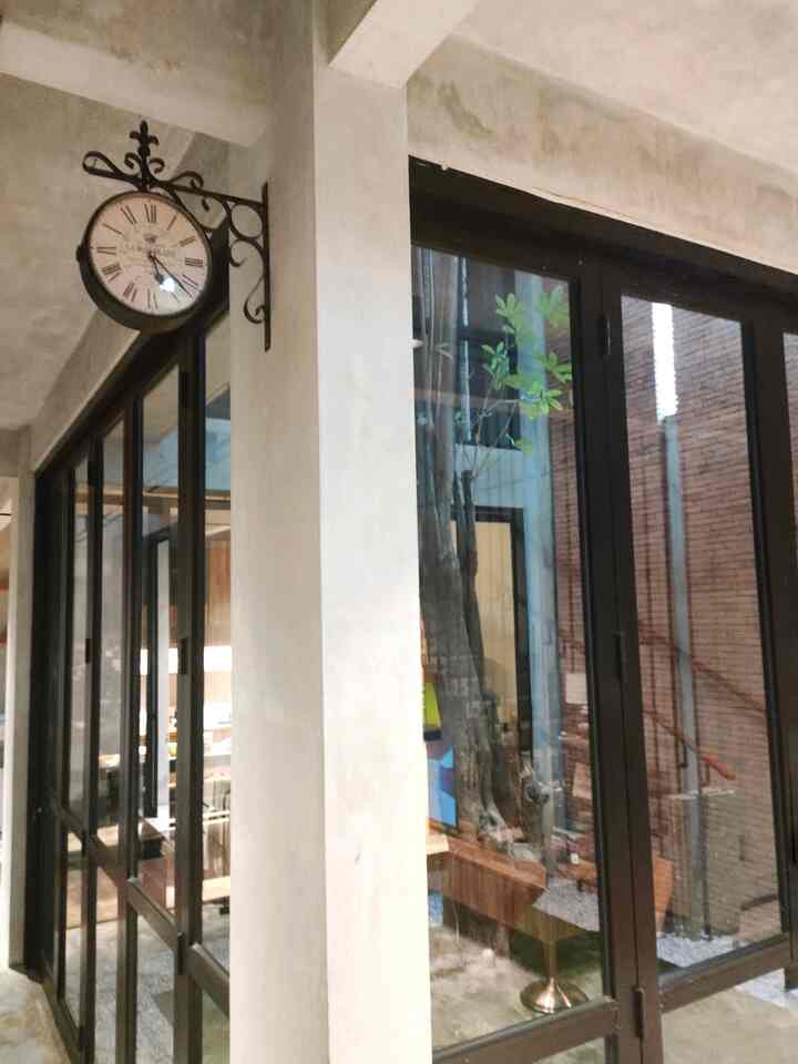 Natural-toned entrance space featuring a vintage wall clock and black-framed glass doors creating a cozy atmosphere
