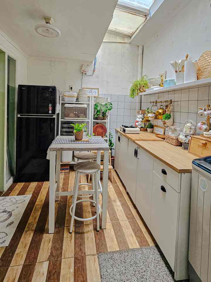 Natural kitchen featuring white and wood tones with a black refrigerator and plants in a narrow cozy space
