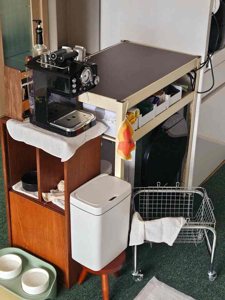白と茶色のトーンの多目的室、ミニ乾燥機や棚、コーヒーマシンが配置された雰囲気のあるミニマルなインテリア