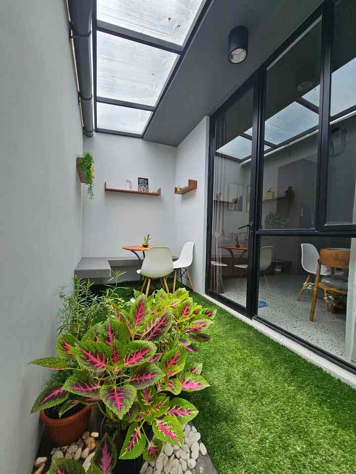 Natural color veranda featuring artificial grass carpet, potted plants, outdoor table and chairs in cozy setting