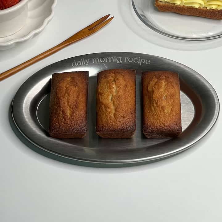 ステンレスの皿に濃い茶色の焼き菓子が3つ並べられたシンプルなテーブルセッティング