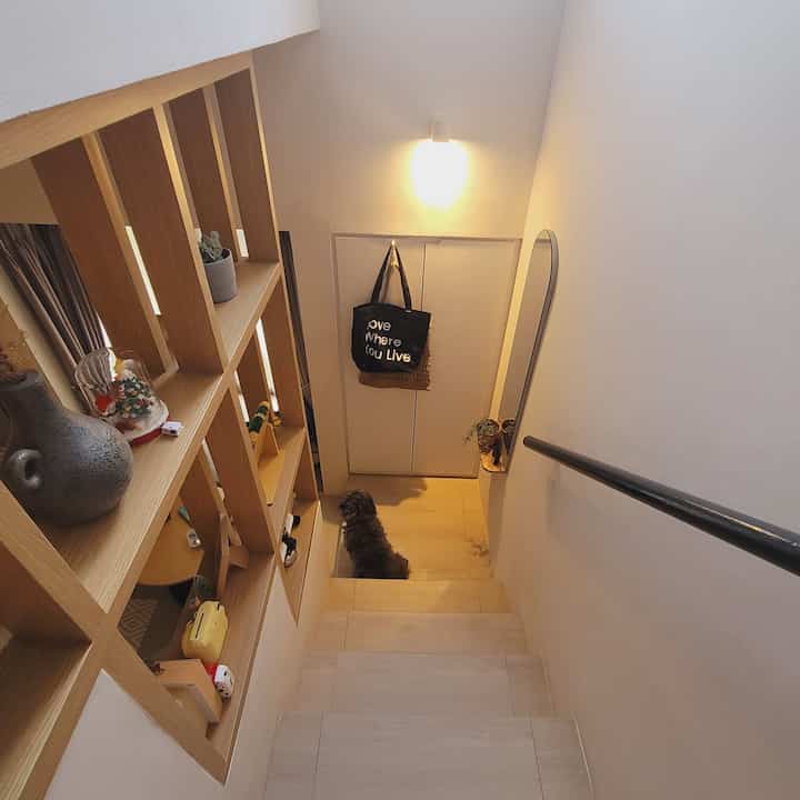 Wood tone and white narrow stair space featuring built-in shelves and a small dog, creating a cozy minimalistic atmosphere