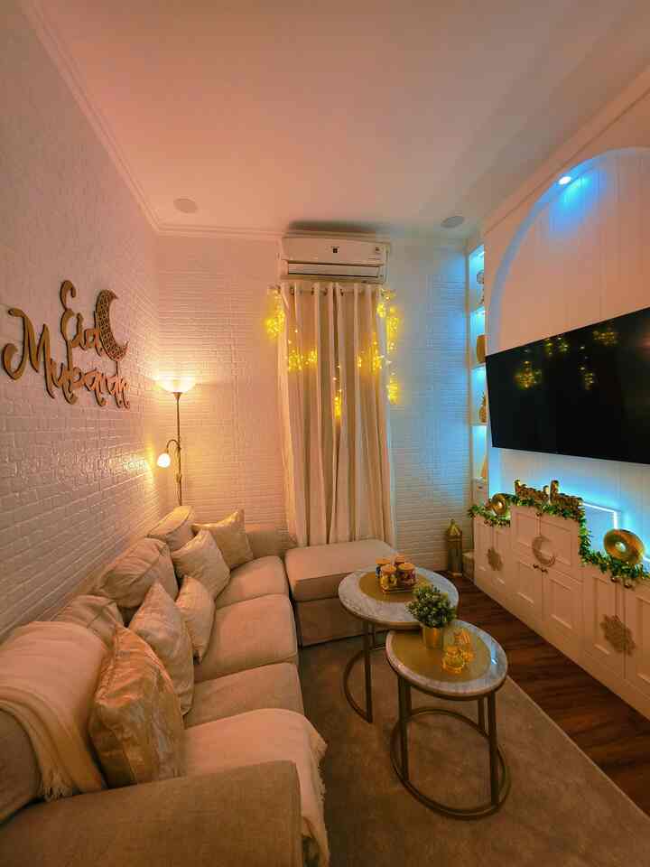 Cozy living room with white walls, beige sofa, string lights, and curtains creating a warm atmosphere