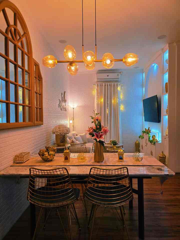 Gold and white toned dining room featuring gold dining chairs and central pendant light, creating a luxurious atmosphere