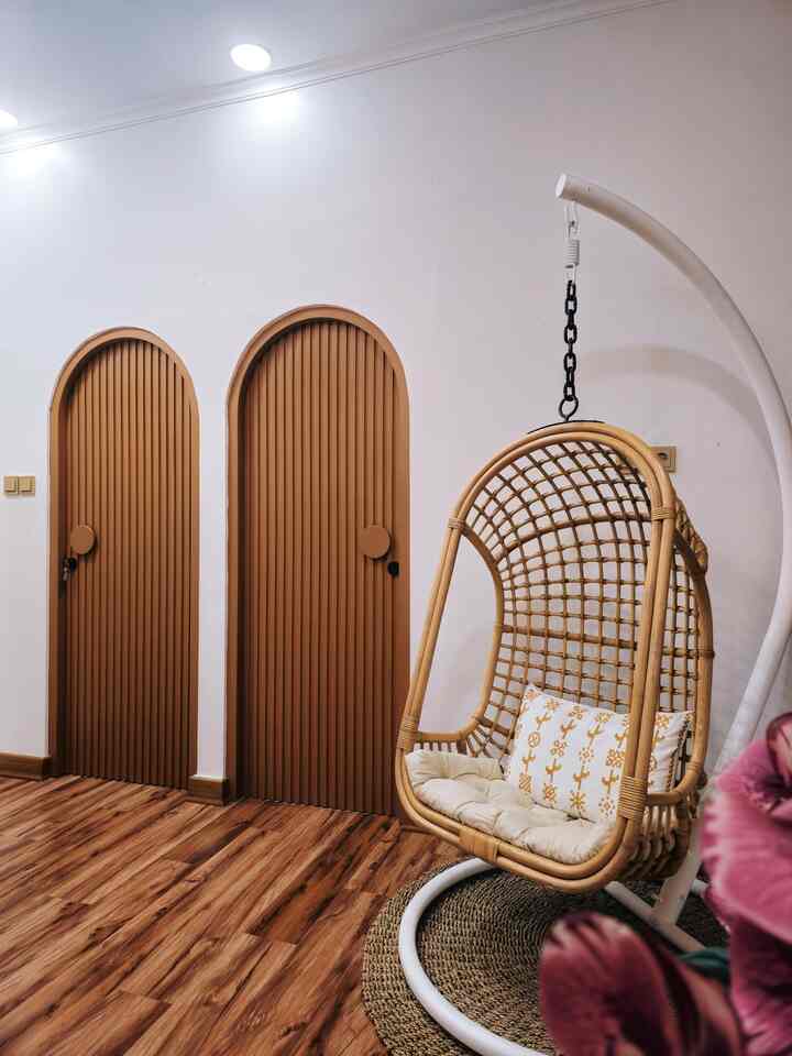 Natural-feeling entrance space with white walls, wood-tone floor, and a rattan hanging chair