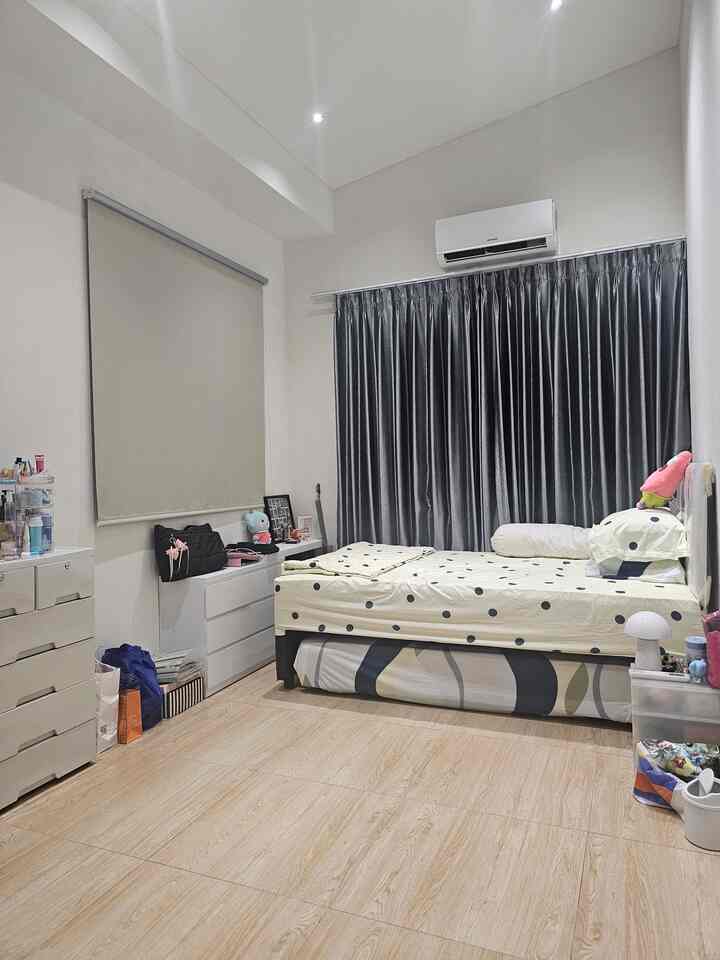 Natural wood tone floor and simple white furniture in a kids' bedroom featuring a bed and curtains in a cozy space