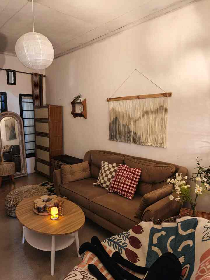 Natural and brown toned living room featuring a sofa, coffee table, ceiling lantern, and storage cabinet creating cozy atmosphere
