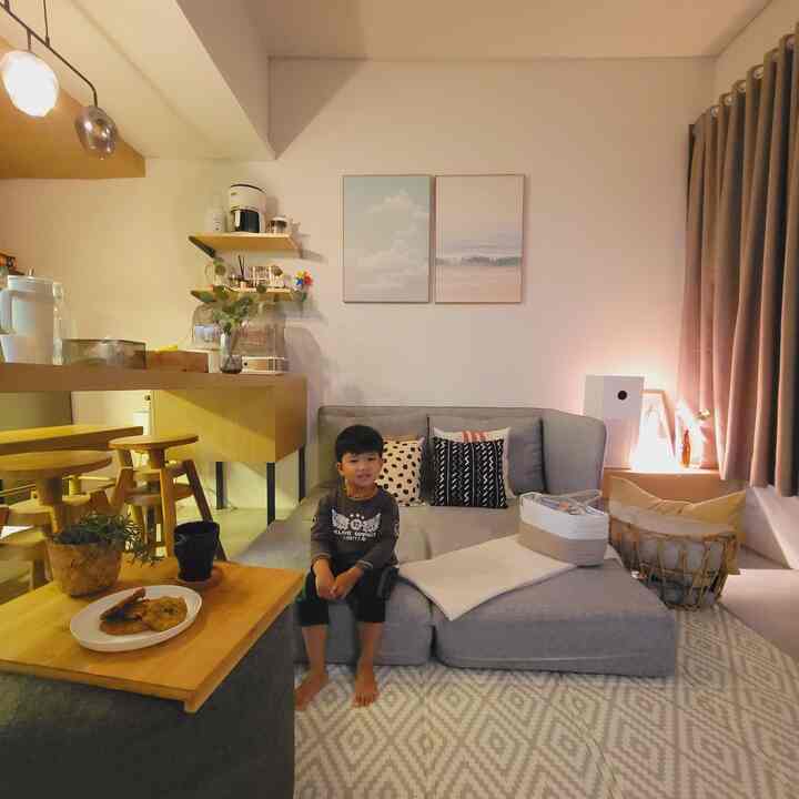 Warmly lit living room featuring a gray sofa bed, wood tone furniture, and an open space ideal for family activities