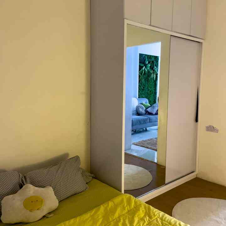 Small bedroom with yellow and white tones featuring a bed and large full-length mirror in a minimal setting