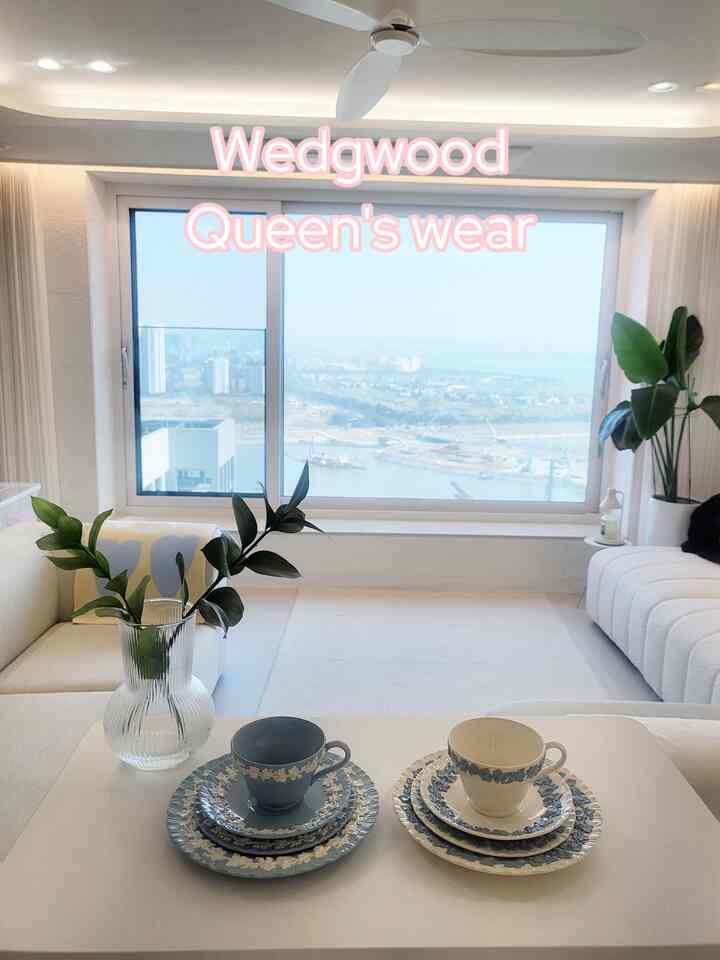 白とラベンダーの色調のリビング、ソファとコーヒーテーブルにウェッジウッドのカップと皿が配置された印象的で清潔感のあるインテリア