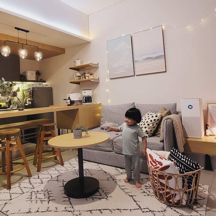 Natural tone compact living room with simple furniture, featuring a child in a cozy space