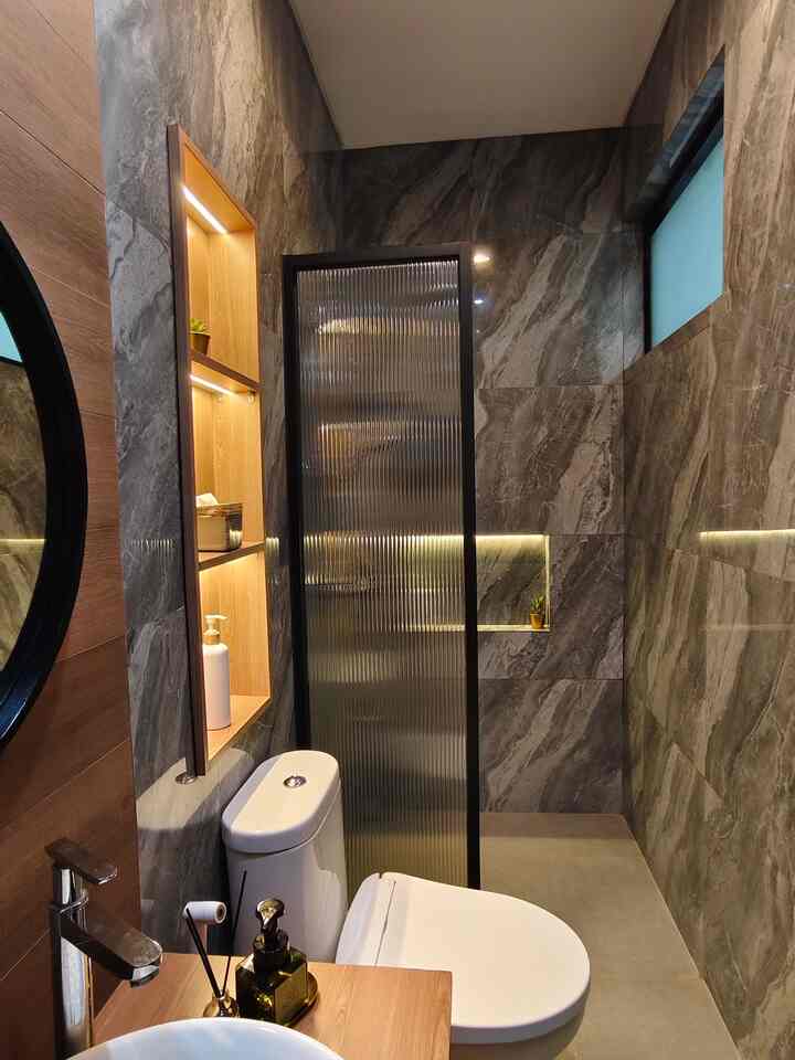 Modern bathroom with gray marble tiles and brown wood tones featuring a shower booth and toilet in a compact space