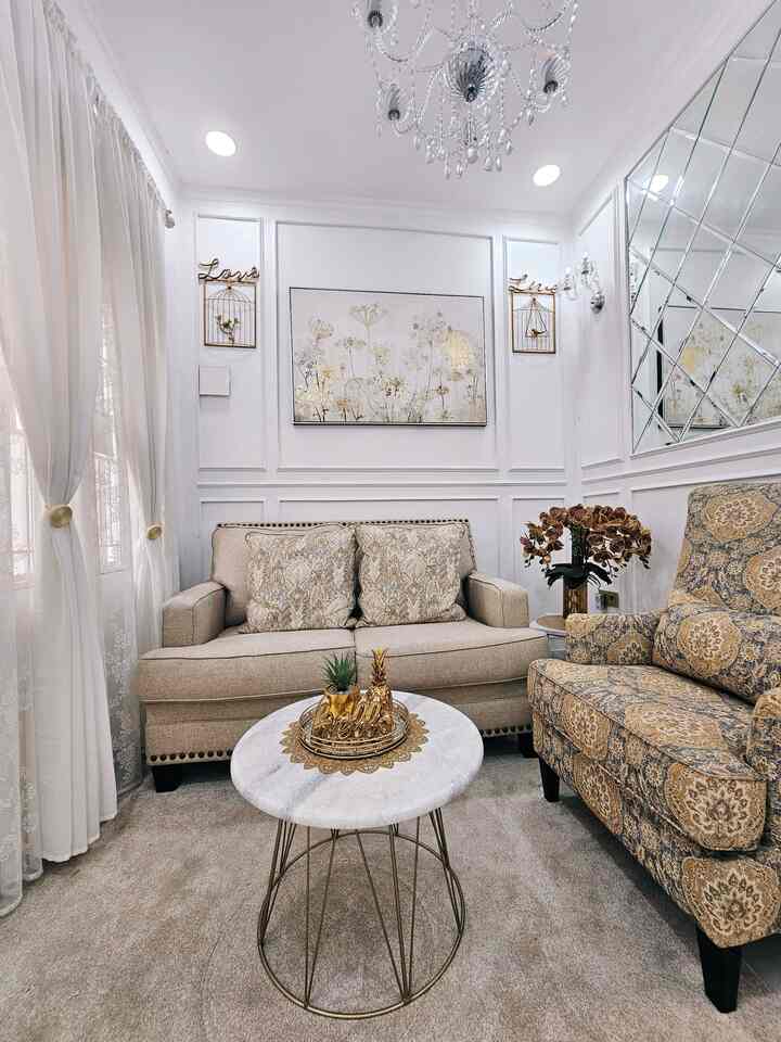 White and gold toned living room featuring beige sofa and patterned armchair in an elegant and cozy space