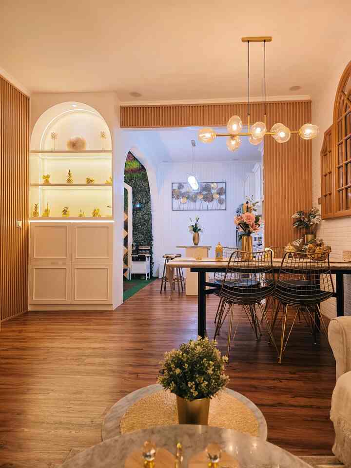 Wood-toned floor and white walls feature in an open plan dining room with gold pendant lighting creating a warm atmosphere