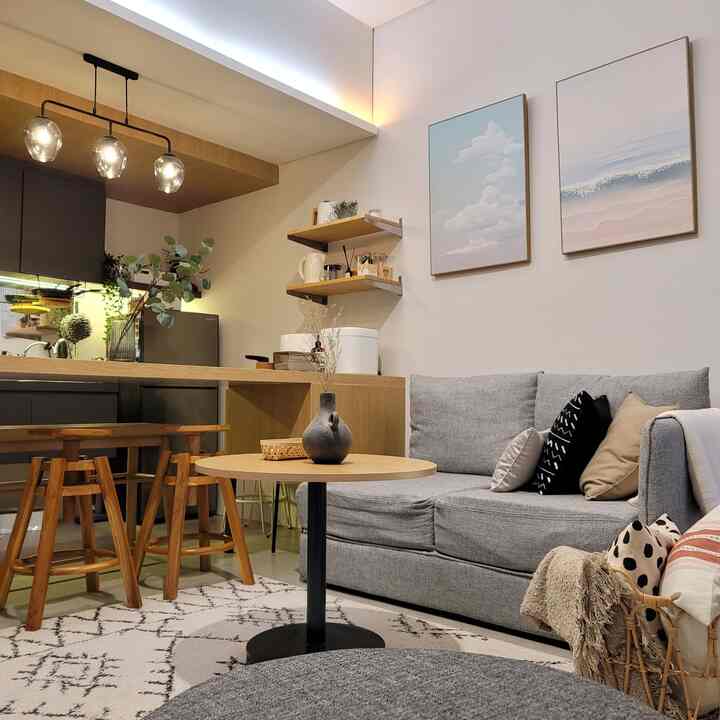 Natural Modern living room and kitchen featuring gray sofa, wood tone bar stools, and pendant lighting with cozy atmosphere