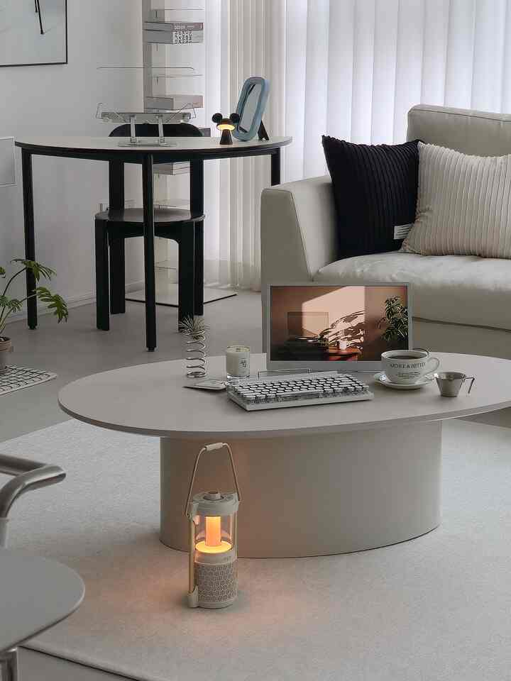 White and gray toned living room featuring a modern sofa, oval coffee table, and coffee cup creating a cozy home cafe atmosphere