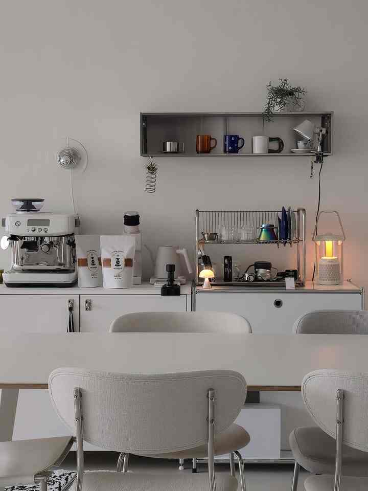 White-toned kitchen space featuring a coffee machine and storage cabinets in a minimal home cafe interior