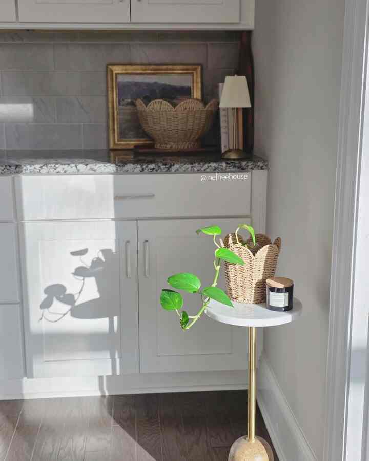 White and gold toned kitchen space featuring a marble round table with plants and candle creating a natural atmosphere
