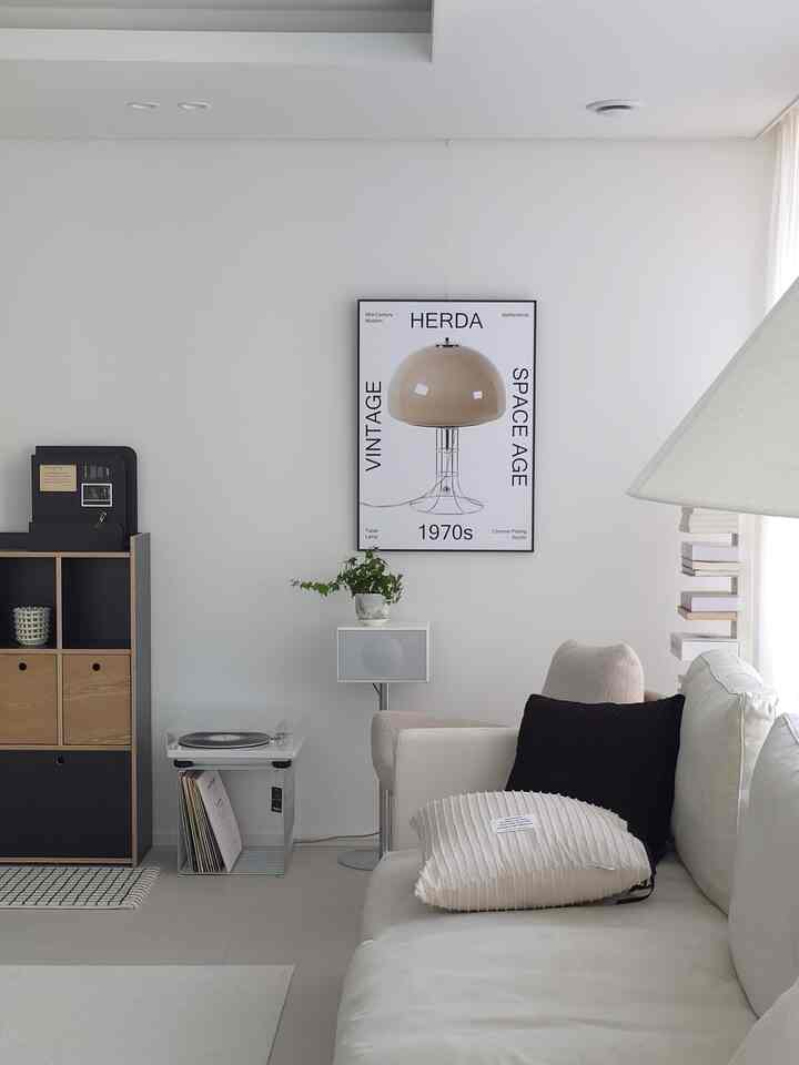 White and beige toned living room featuring a modern sofa and black-framed poster for a simple, stylish space