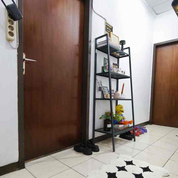 Minimal entrance with white walls and wooden doors in a narrow hallway, featuring black metal rack and monochrome carpet for a cozy vibe