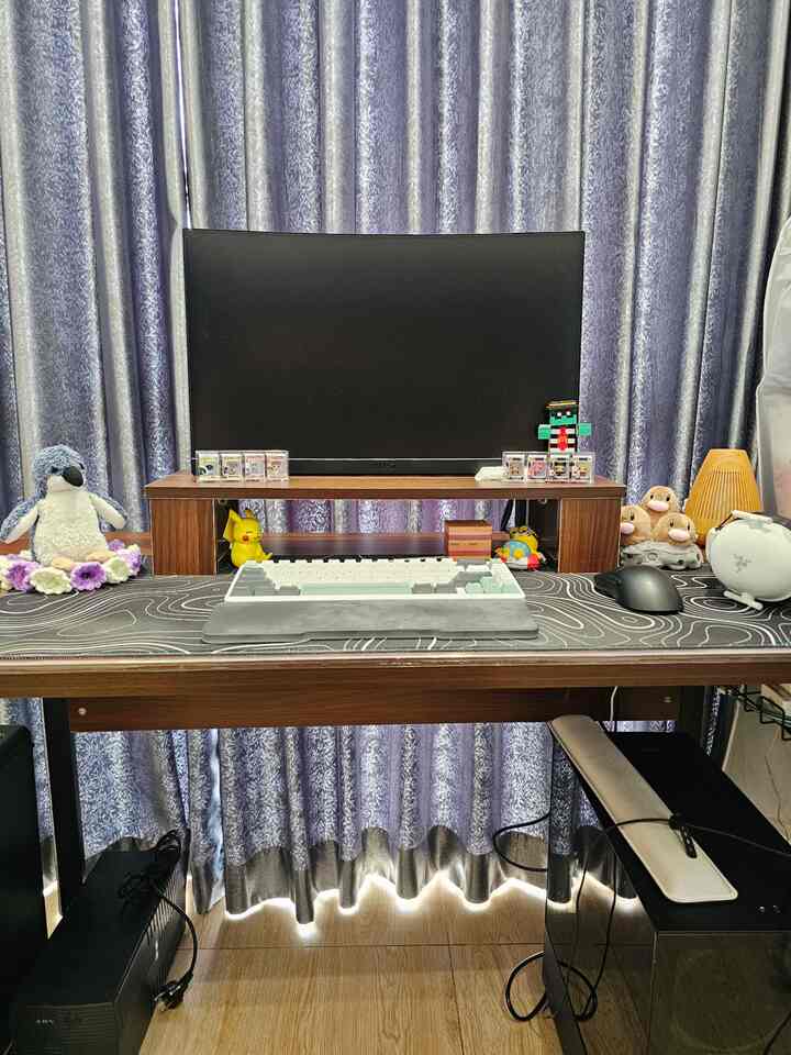 Wood tone and black toned home office space featuring a desk with monitor centered and various decorative items