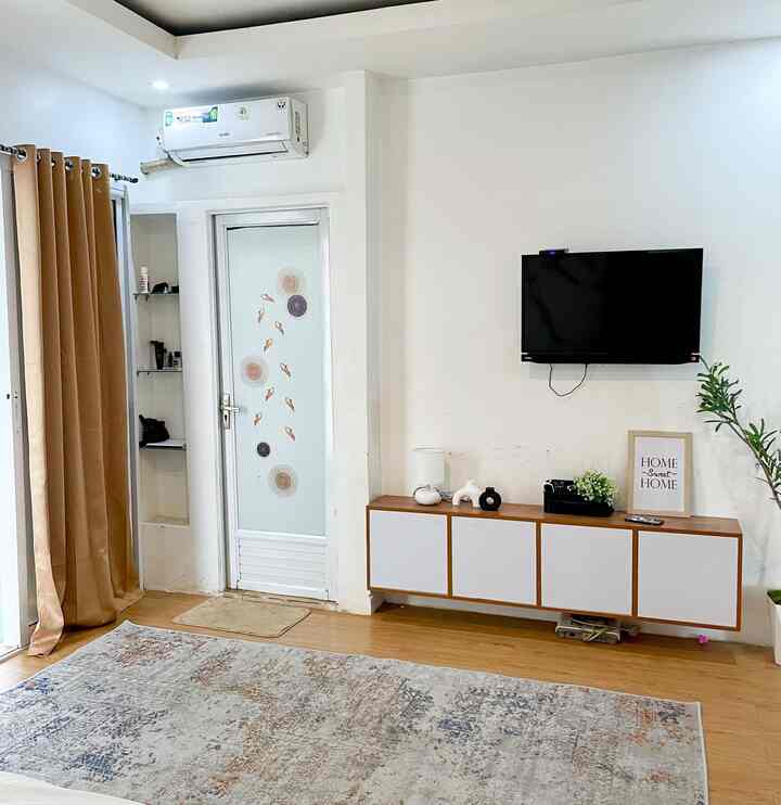 Living room with white walls and wood tone flooring, featuring wall-mounted TV and floating storage cabinet, creating a simple atmosphere