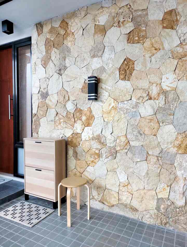Brown and natural toned entrance featuring a stone wall and wooden shoe cabinet in a cozy space