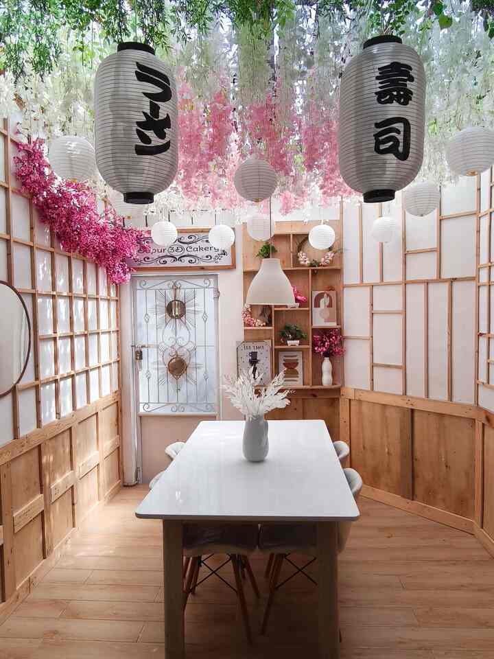 Wood tone and white dominant dining room with pink floral decorations, evoking a warm Japanese restaurant atmosphere