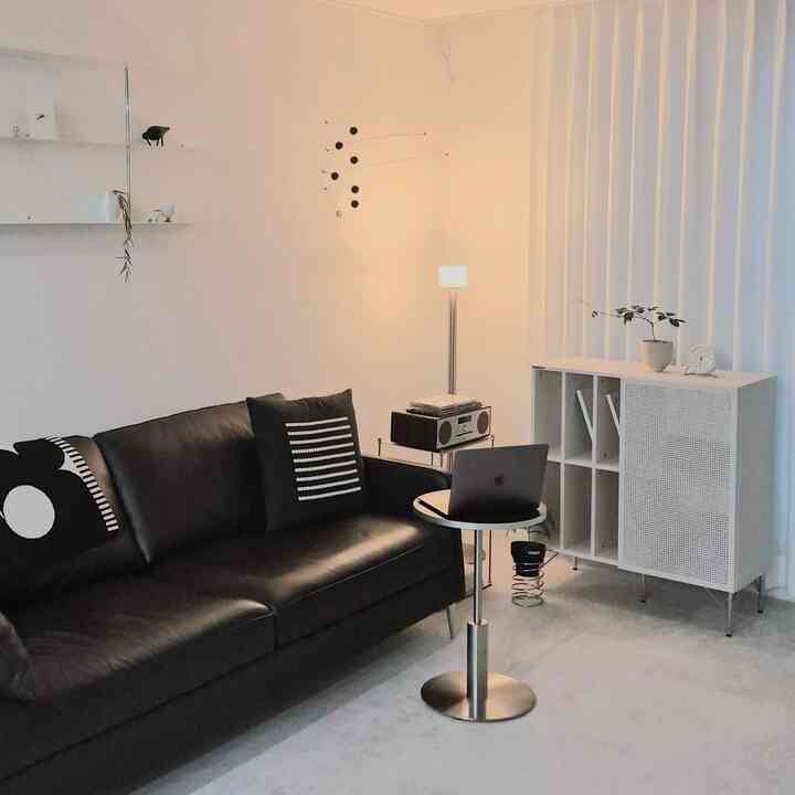 White-toned living room featuring a black sofa and floor lamp with a clean modern mood