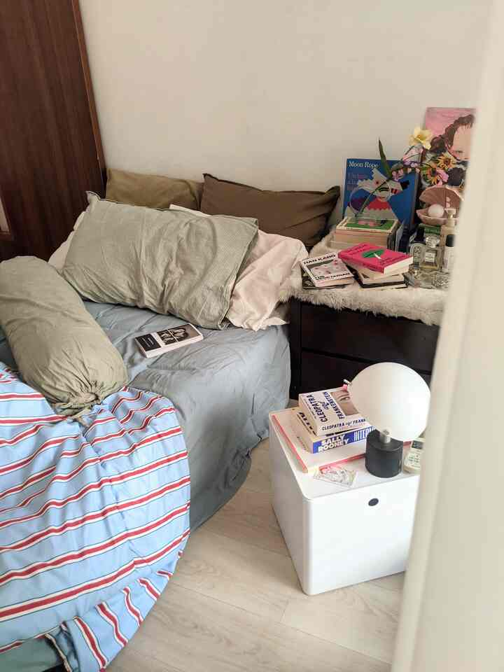 White-walled bedroom with brown fabrics, featuring books and warm lighting creating a cozy atmosphere