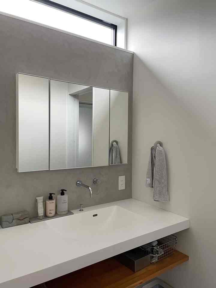 Simple bathroom space in white and gray tones featuring a wide sink, mirror, and towels with a clean interior