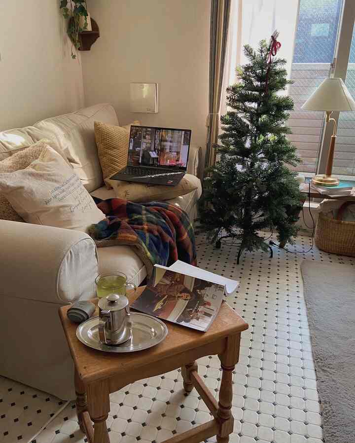 白と木目調のリビング、ソファやコーヒーテーブル、クリスマスツリーとランプが配置された雰囲気のあるインテリア