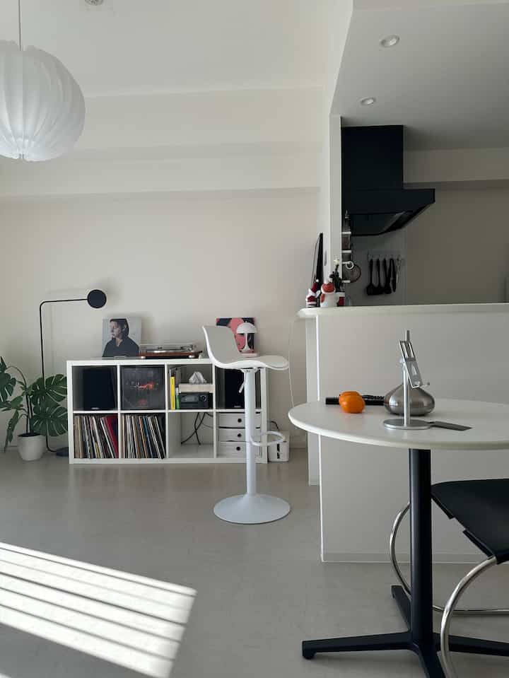 ホワイトとブラックのトーンのコンパクトなリビング、ミニマルな家具と植物が配置された印象的な空間