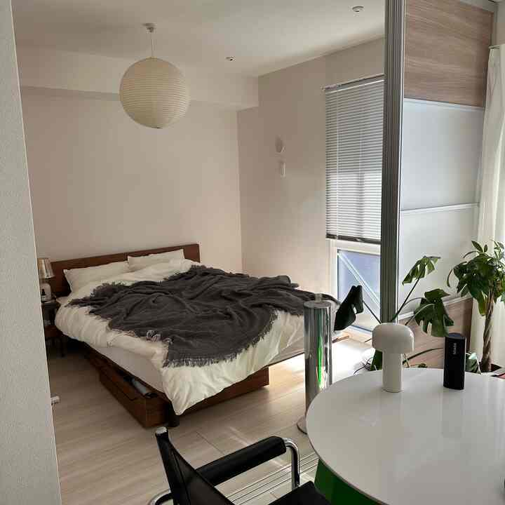 白と木目調の調和が美しいモダンな寝室、中央にベッドとスライディングクローゼットが配置され、自然光と植物が雰囲気を作る空間