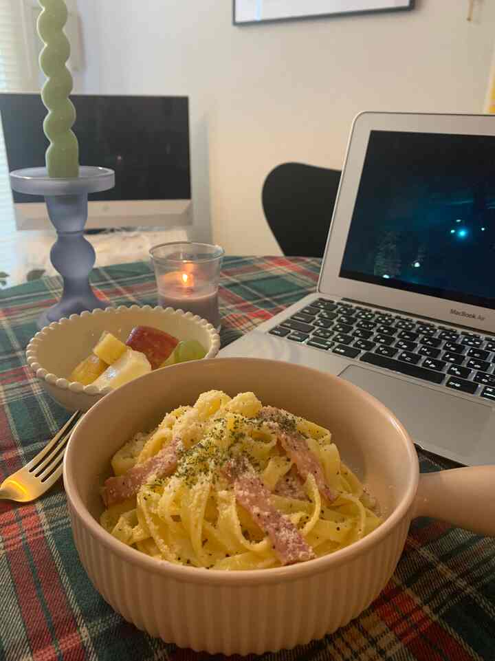 緑と赤のタータンチェック柄テーブルクロスが敷かれた、ランチとノートパソコンのある小さくて居心地の良いダイニングスペース