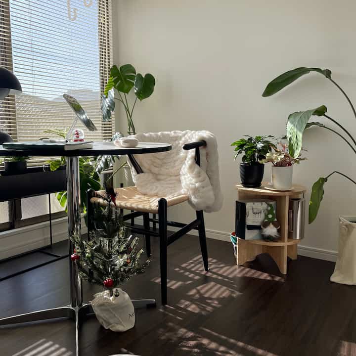 自然な木目調と白を基調とした韓国インテリアのリビング、観葉植物とモダンなアームチェアが配置された雰囲気のある空間