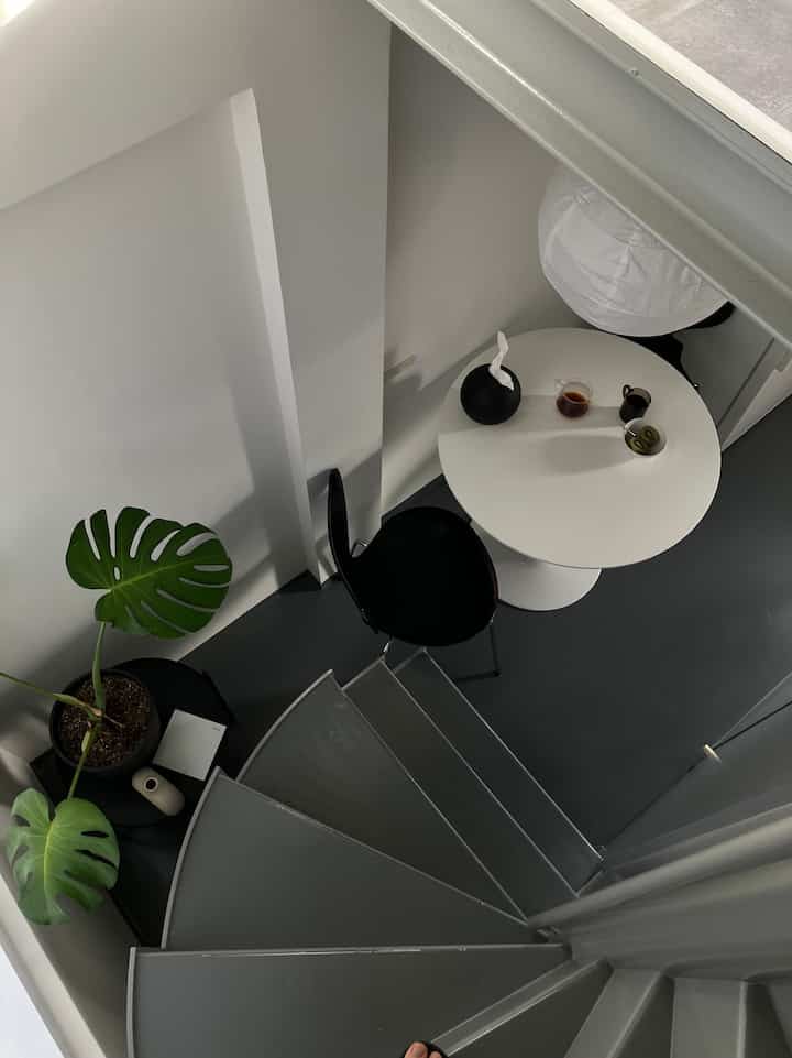 ホワイトとブラックのトーンでまとめられたミニマルな一人暮らし用ダイニング、丸テーブルと黒い椅子が配置されたシンプルな空間