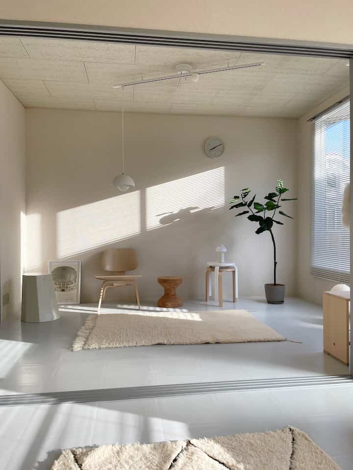 Minimal compact room in white and beige wood tones featuring single wooden chair and pendant light with calm atmosphere