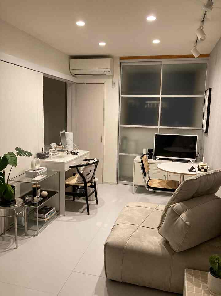 White-toned compact living room featuring a natural beige sofa and rattan chairs in a simple, minimal space