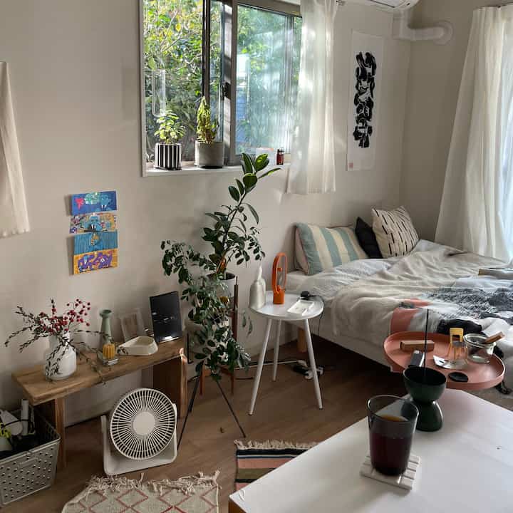 白と木目調の寝室、窓際に植物が配置された自然な雰囲気の落ち着いた空間