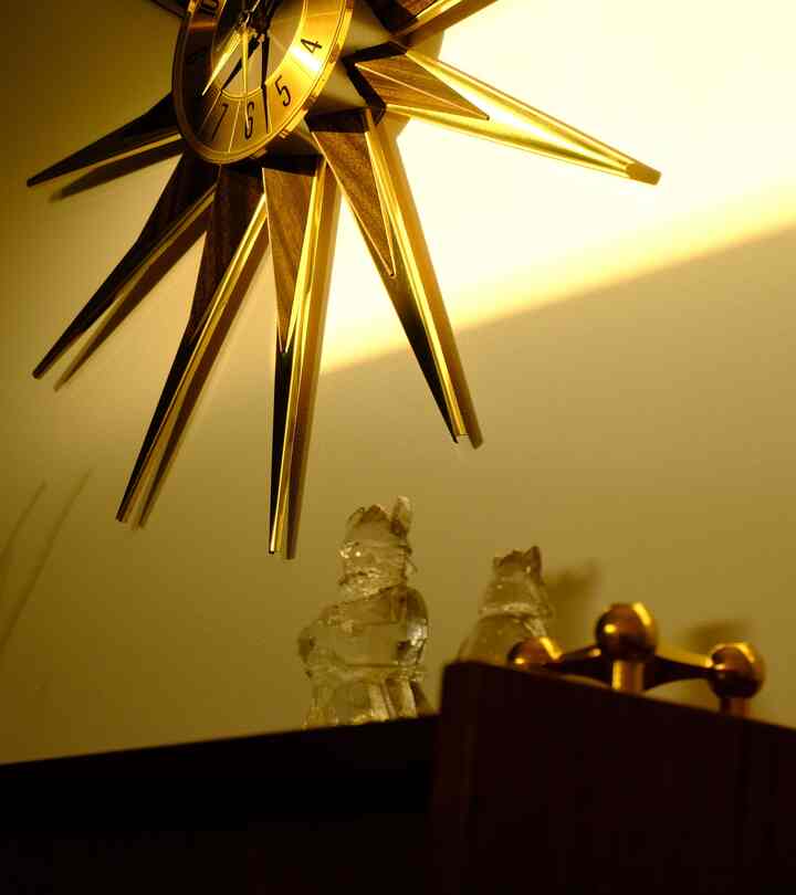 ゴールドのウォールデコが印象的な空間、透明なガラスのオブジェが置かれた温かみのあるインテリア